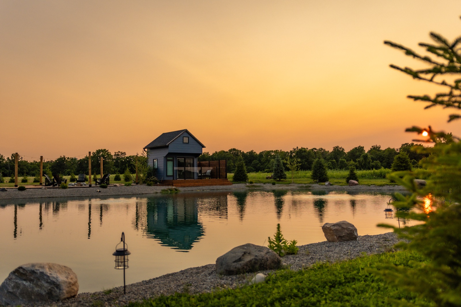 Rocks, evergreens, and sunset light at the pond's edge